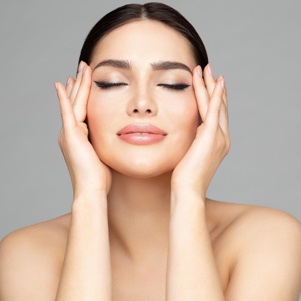 Femme aux yeux fermés touchant doucement son visage, illustrant des soins médico esthétiques